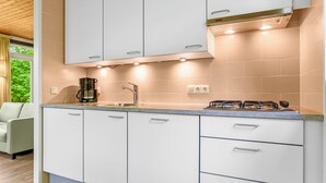 A modern kitchen with white cabinets, a gas stove, and a coffee maker.