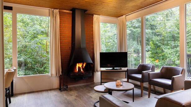 A cozy living room with a fireplace, large windows, and comfortable seating.
