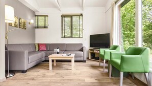 Una sala de estar moderna con un sofá gris, una mesa de centro de madera, un televisor de pantalla plana y sillas verdes.