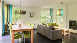 A modern living room with a sofa, chairs, a dining table, and a fireplace. - Markegaerde Wellness 4 (Ruinen)