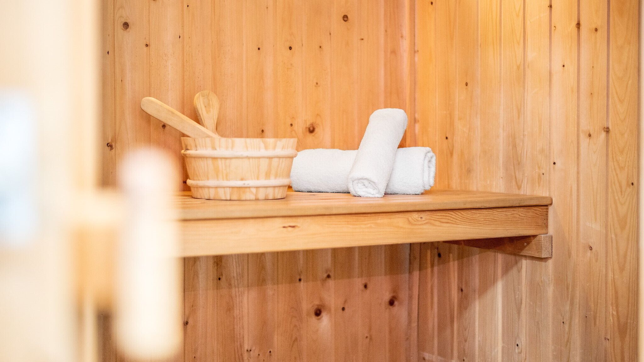 Een houten plank met een houten kom, een houten lepel en twee opgerolde handdoeken.