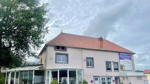 A hotel with a red-tiled roof, a signboard advertising a restaurant, and a parking lot. - Les Jardins de Saulzet (Romagnat)