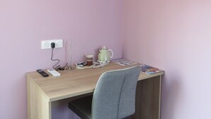 A small, neatly organized room with a desk, chair, and an air conditioner mounted on the wall. - Les Jardins de Saulzet (Romagnat)