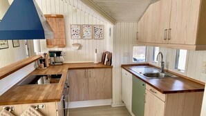 Une cuisine moderne avec des meubles en bois, un lave-vaisselle encastré et une fenêtre qui laisse entrer la lumière naturelle.
