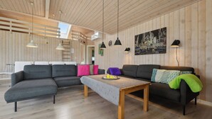 A modern living room with a sectional sofa, a coffee table, pendant lights, and a cityscape painting on the wall. - Activity house - Flovt Strand, Haderslev (Haderslev)