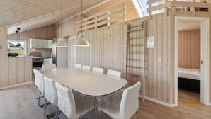 A modern kitchen with white cabinets, a large round table, and pendant lighting. - Activity house - Flovt Strand, Haderslev (Haderslev)