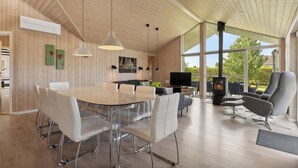 A spacious room with a wooden ceiling, a large dining table with chairs, a sofa, and a television. - Activity house - Flovt Strand, Haderslev (Haderslev)
