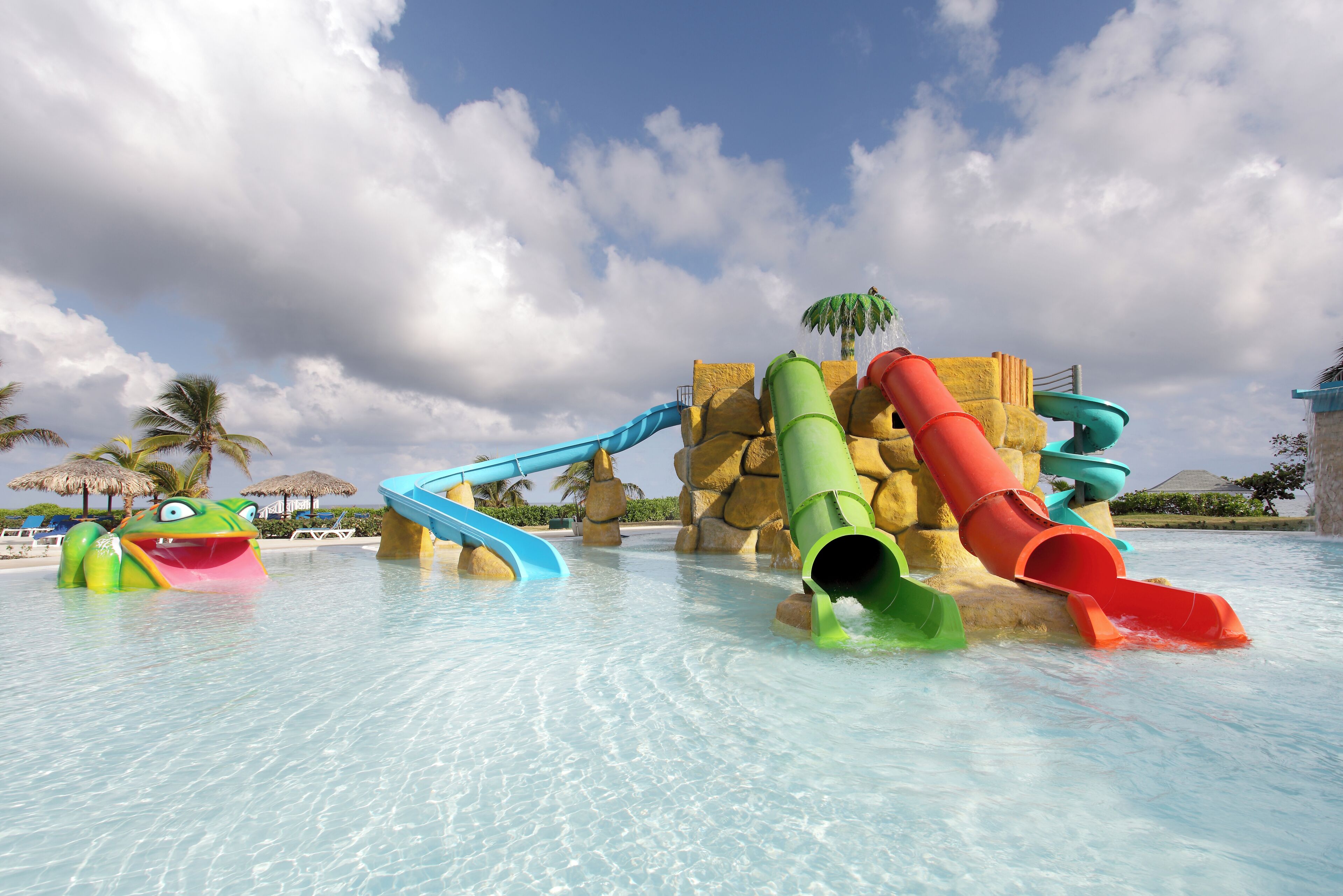 A water park with multiple slides and a large rock formation in the background.