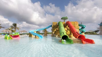 A water park with multiple slides and a large rock formation in the background.