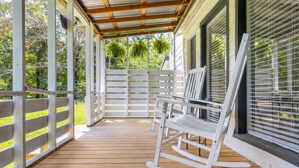 A covered porch with a wooden floor, white rocking chairs, and a white fence. - The Meadow! Peaceful Getaway! (Chattanooga Valley)
