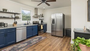 A modern kitchen with blue cabinets, stainless steel appliances, a dishwasher, and a ceiling fan. - The Meadow! Peaceful Getaway! (Chattanooga Valley)