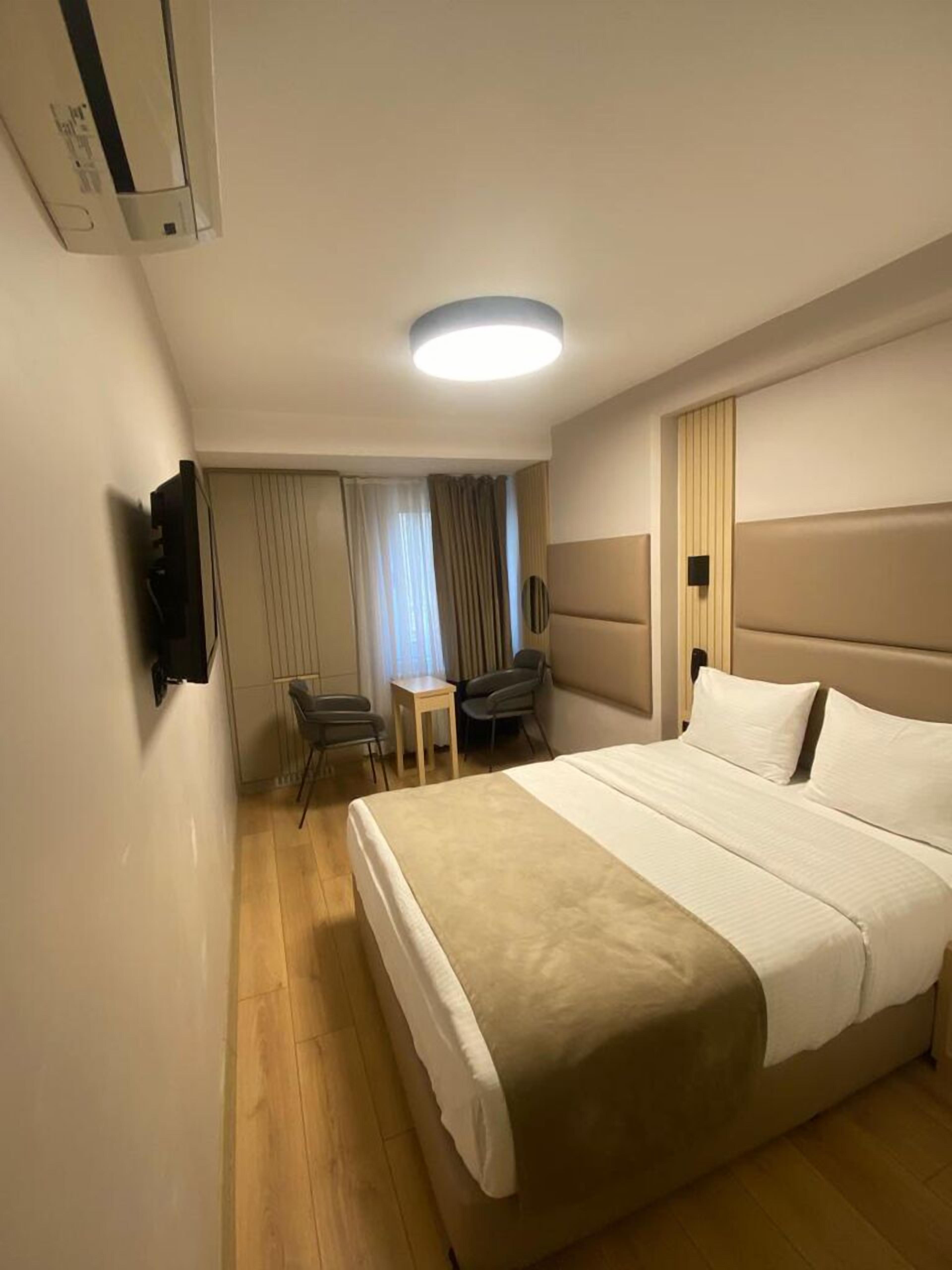 Ett hotellrum med en stor säng, ett skrivbord, en stol och en tv som är monterad på väggen.