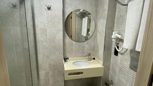 Un bagno con doccia vetrata, lavandino con specchio sopra e water.