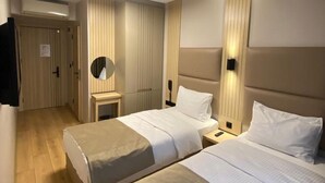 Una camera d'albergo con due letti, uno specchio, comodini e una lampada a soffitto.