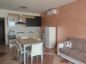 Una cocina compacta con mesa, sillas, un refrigerador y un sofá.