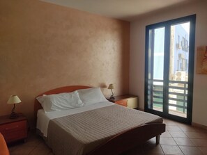 Una camera da letto con un letto, comodini, una finestra vista e una porta.