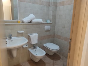 Un baño con lavamanos, bidé, inodoro y espejo.