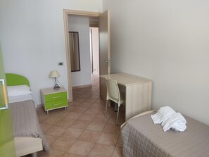 Un dormitorio con cama, escritorio, silla, mesita de noche y espejo.