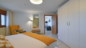 A bedroom with a bed, a chair, a wardrobe, and a door leading to another room. - Apartment Mi Mexico Benissa Costa (Benissa)
