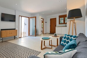 Un salon moderne avec un canapé, une table basse, un téléviseur et une lampe.