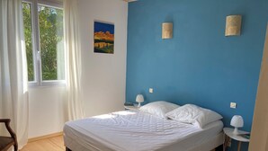 A bedroom with a bed, a nightstand, a lamp, a power outlet, a window with curtains, and a painting on the wall. - Vacation home on enclosed land 800 metres from the beach and shops (Mesquer)