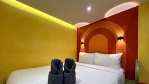 Ein Hotelzimmer mit einem Bett, weißer Bettwäsche und einem Paar dunkler Handtücher auf dem Bett.