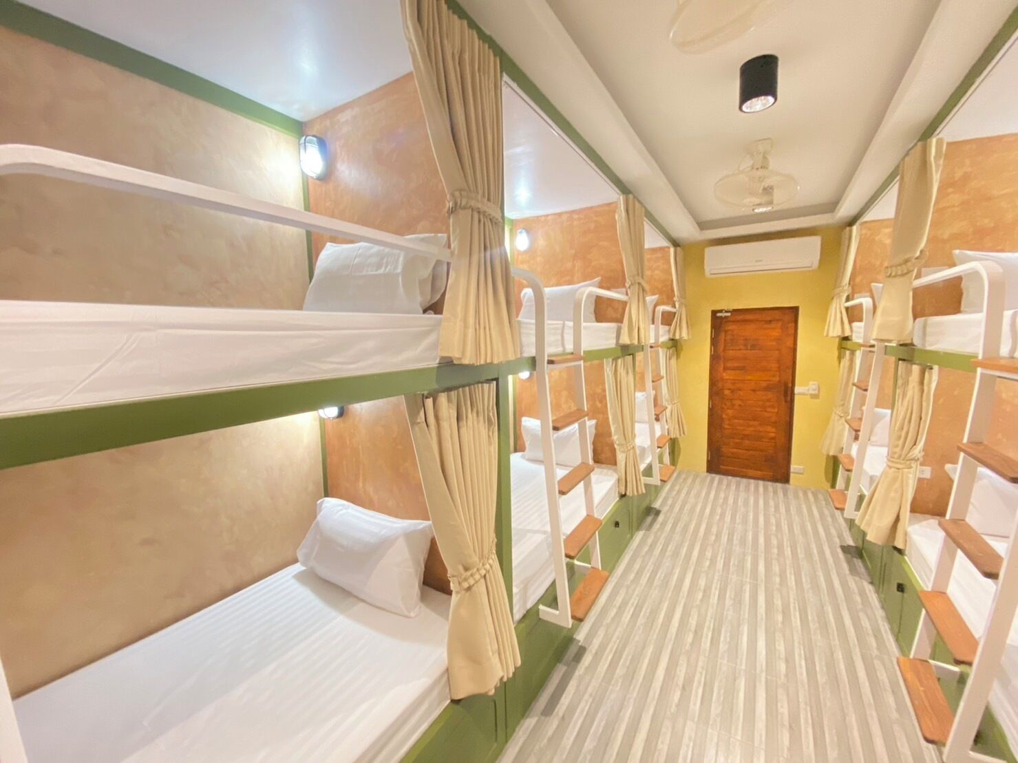 A room with bunk beds, a wooden door, and a ceiling fan.