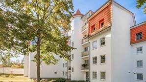 A multi-story residential building with a white facade, red roof tiles, and a central tower. - Beautiful vacation apartment in Heringsdorf with terrace - only 400 m to the beach (Seebad Heringsdorf)