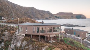Ein modernes Haus mit Balkon mit Blick auf eine Küstenlandschaft.