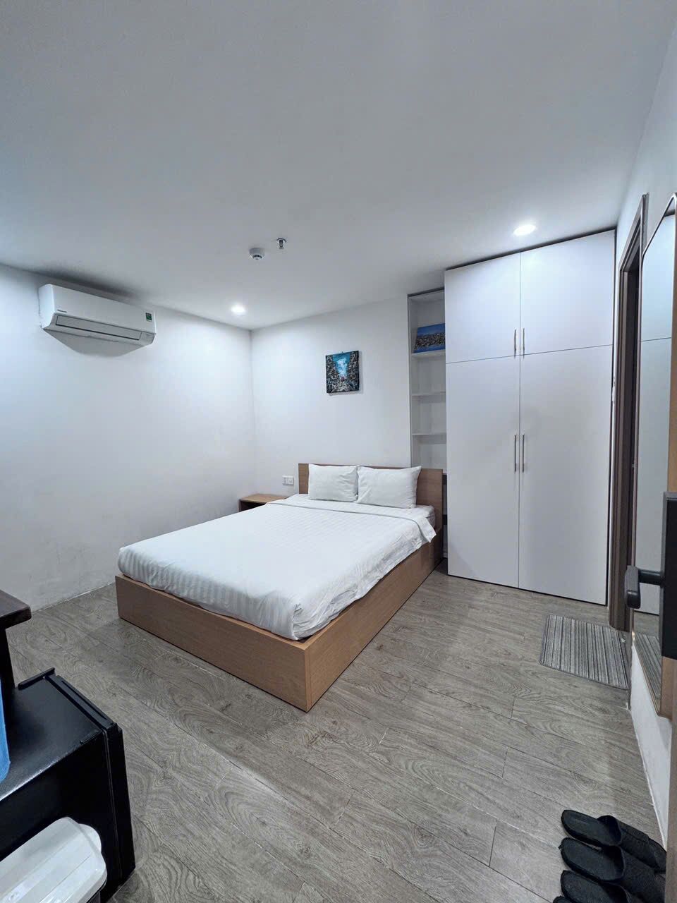 A modern bedroom with a bed, wardrobe, and a small table.