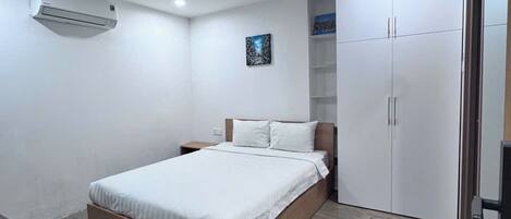 A modern bedroom with a bed, wardrobe, and a small table.