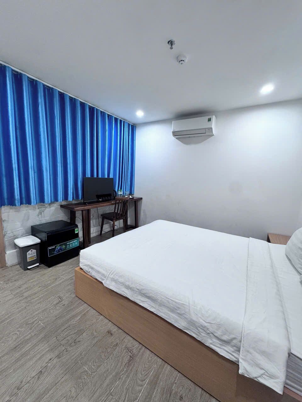 Ein Hotelzimmer mit Bett, Schreibtisch, Computer, Stuhl und Papierkorb.