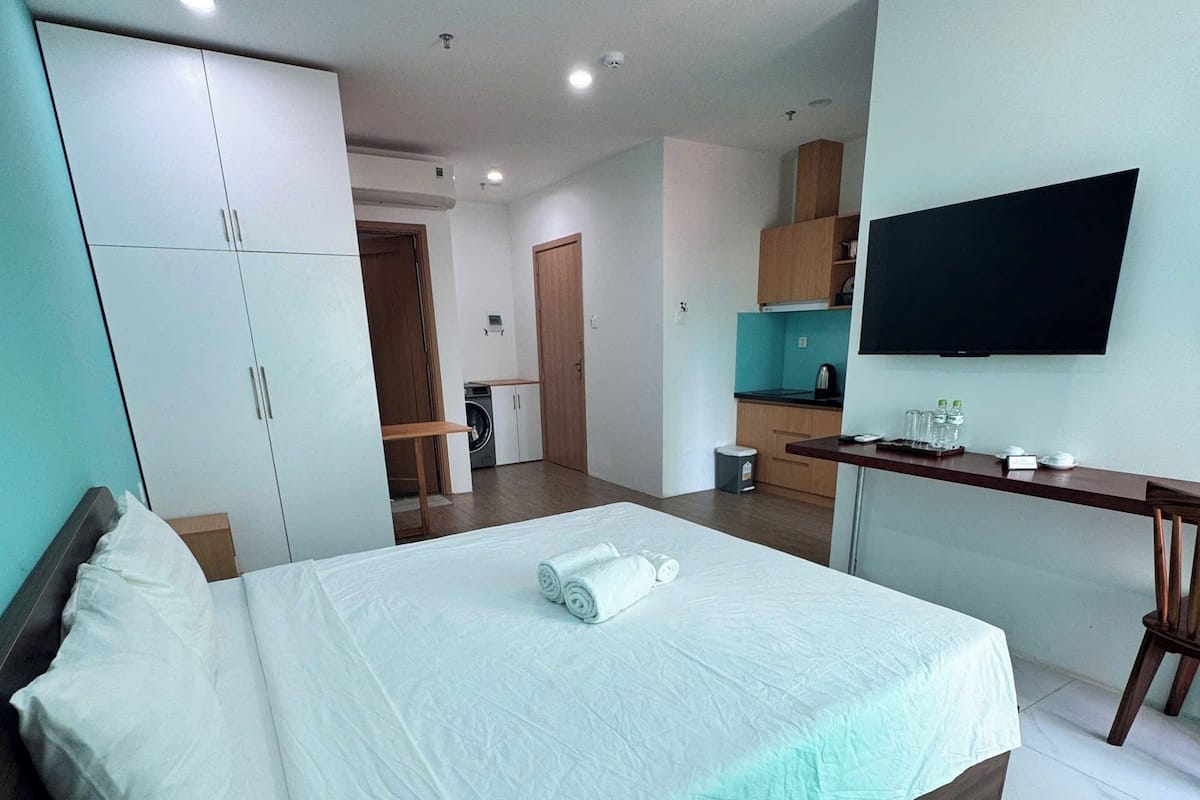 Ein modernes Hotelzimmer mit einem großen Bett, einem Schreibtisch, einem Fernseher und einer Küchenzeile.