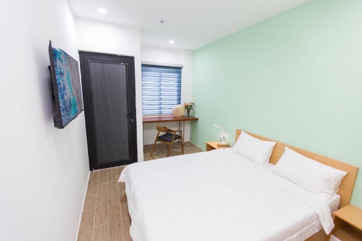 Ein Schlafzimmer mit Bett, Schreibtisch, Stuhl und einer Tür.