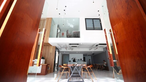 Un amplio vestíbulo de hotel con techo alto, un área de estar central y una escalera visible que conduce a un piso superior.
