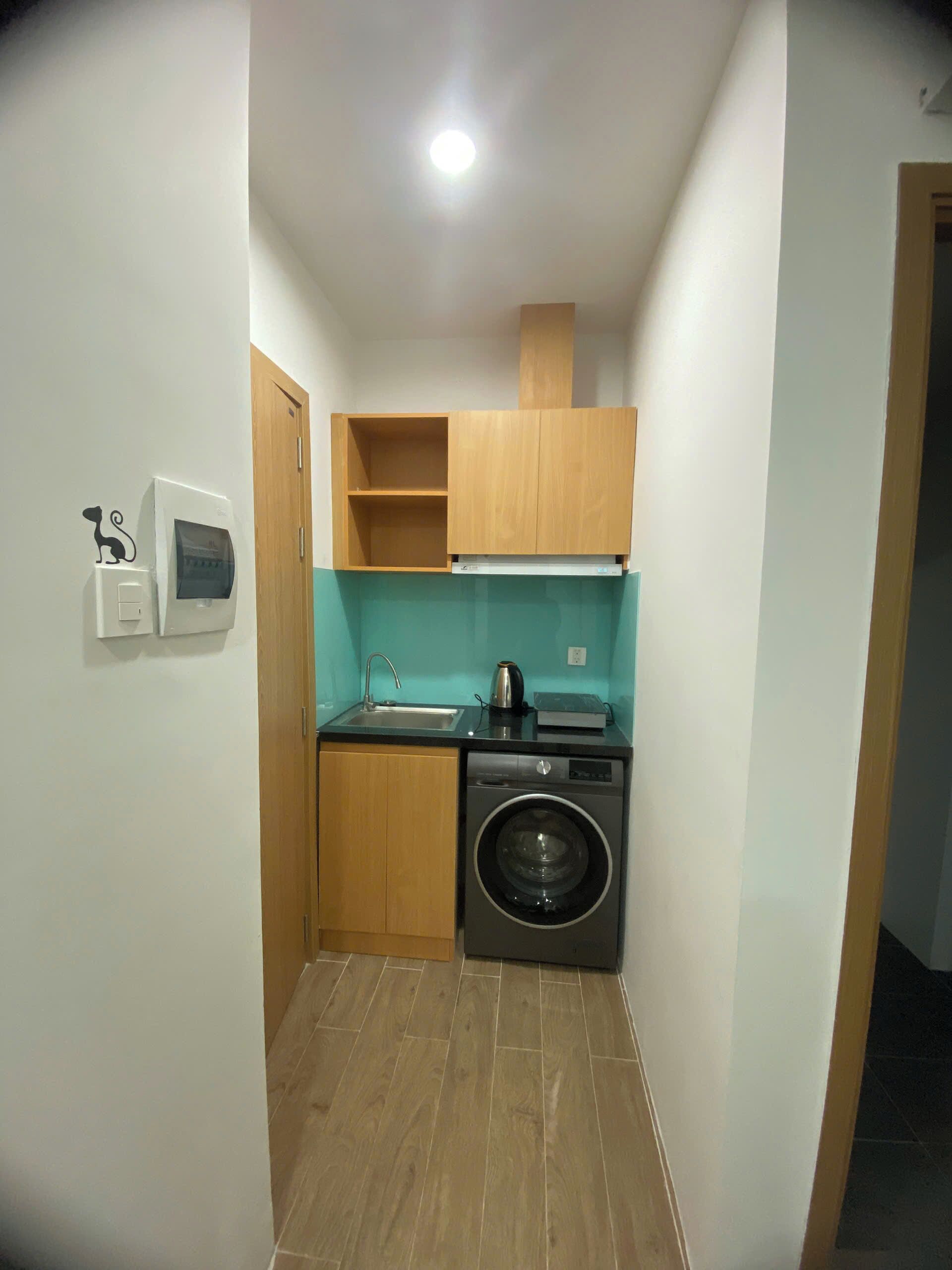 A compact kitchen with a washing machine, a sink, and wooden cabinets.
