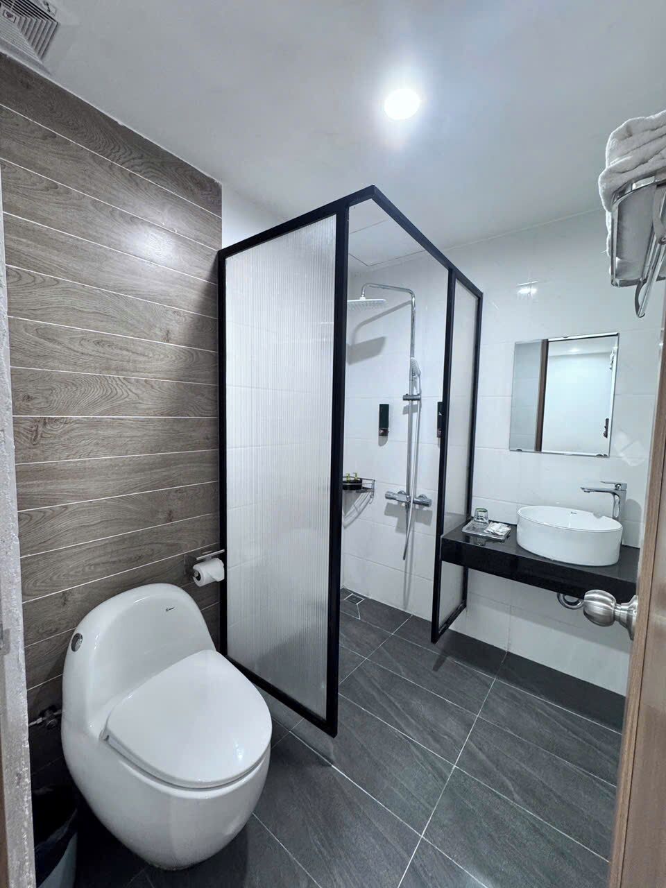 A modern bathroom with a toilet, shower, and sink.