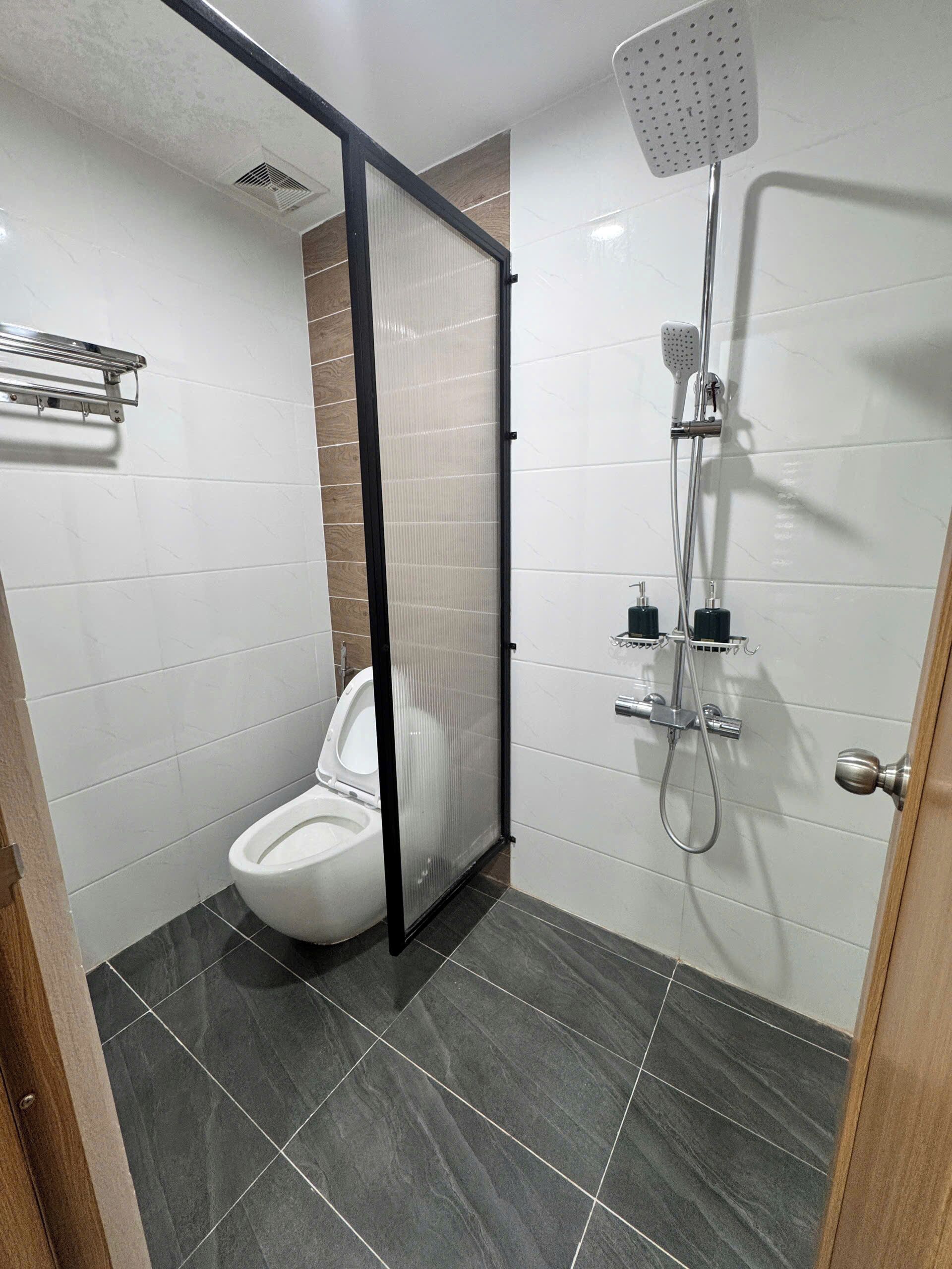 Une salle de bain moderne équipée de toilettes, d’une douche et d’une paroi en verre.