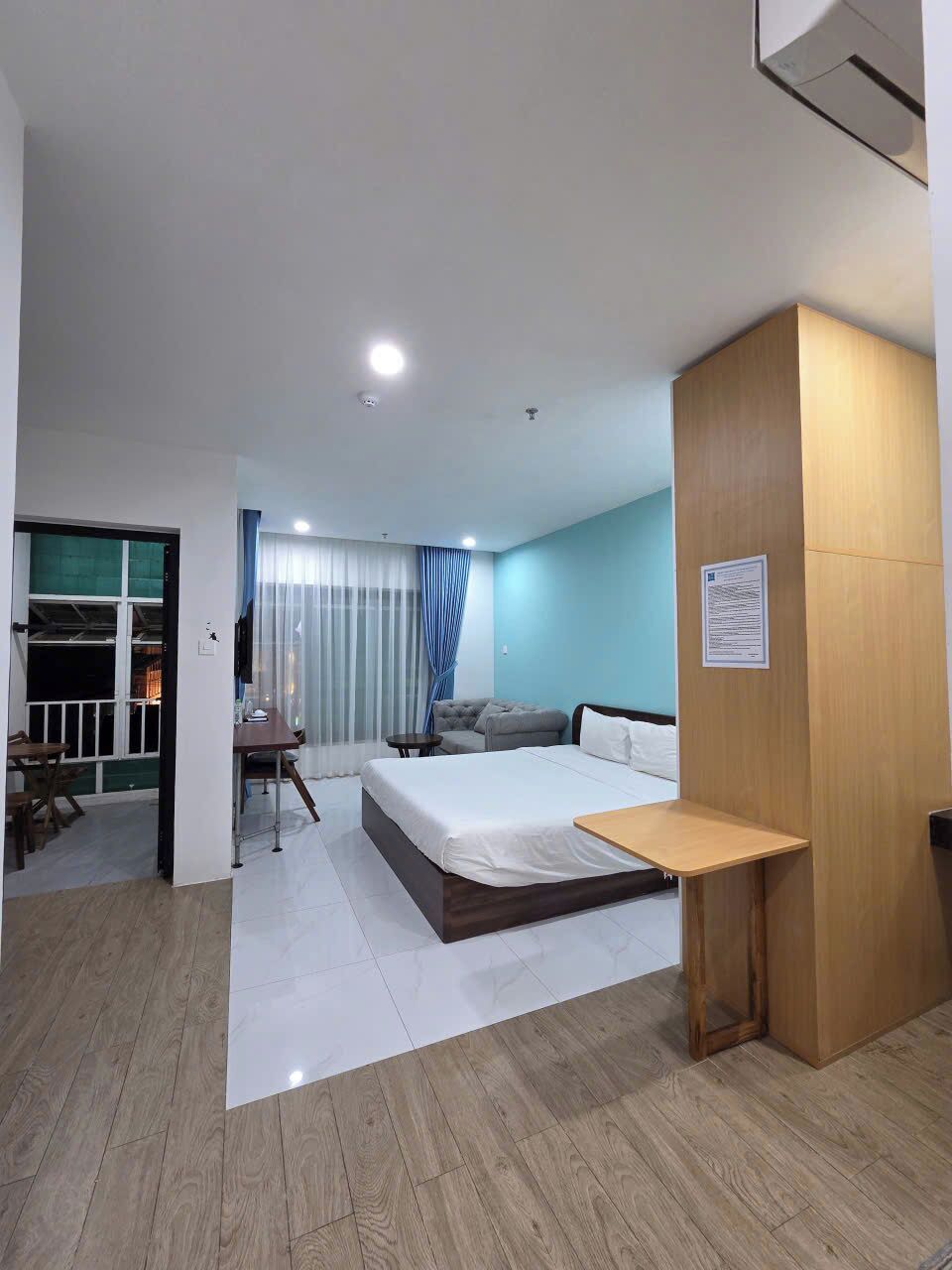 A hotel room with a bed, a desk, a chair, a small table, and a TV.