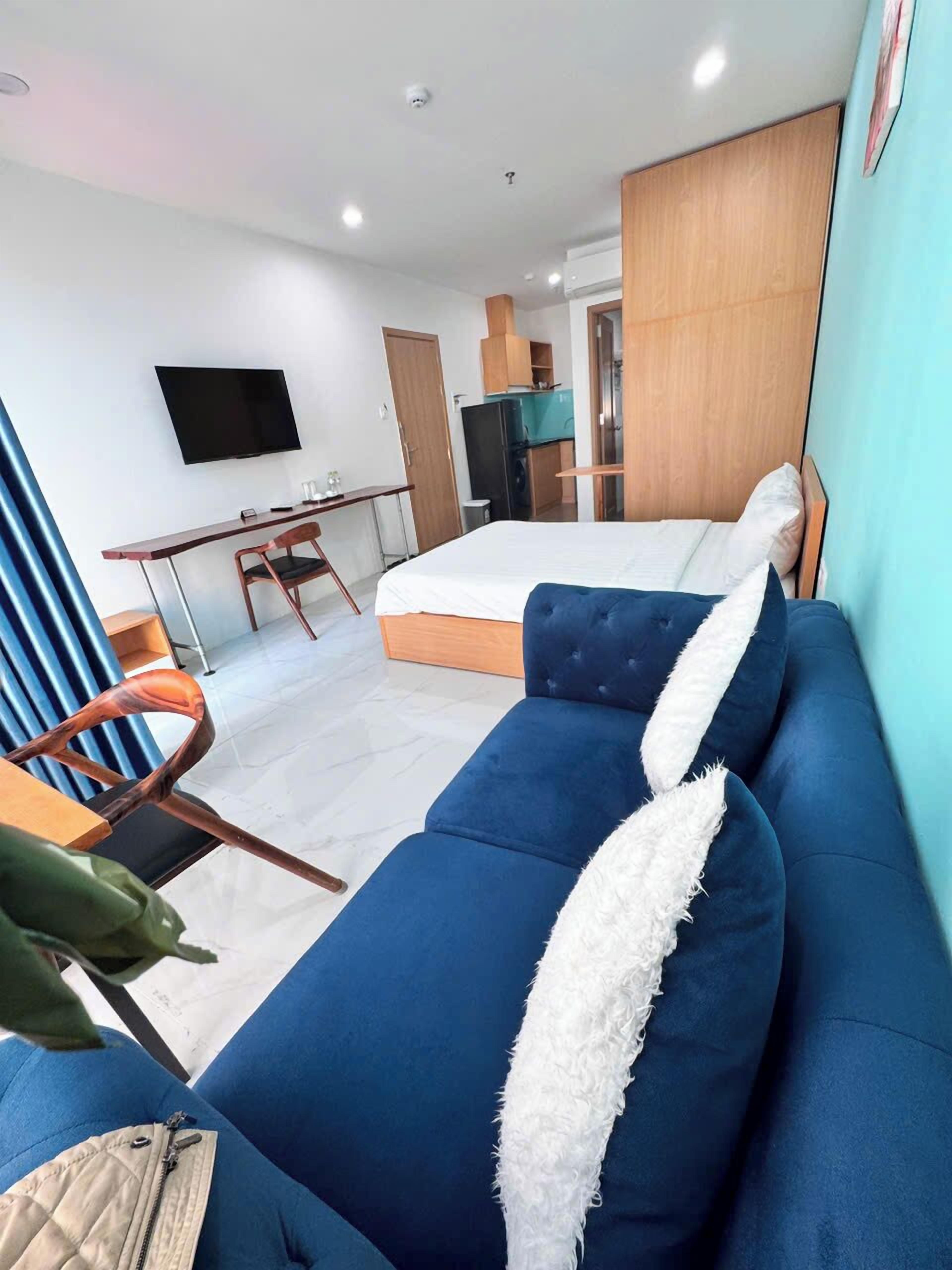A modern hotel room with a large bed, a sofa, a desk, and a TV.