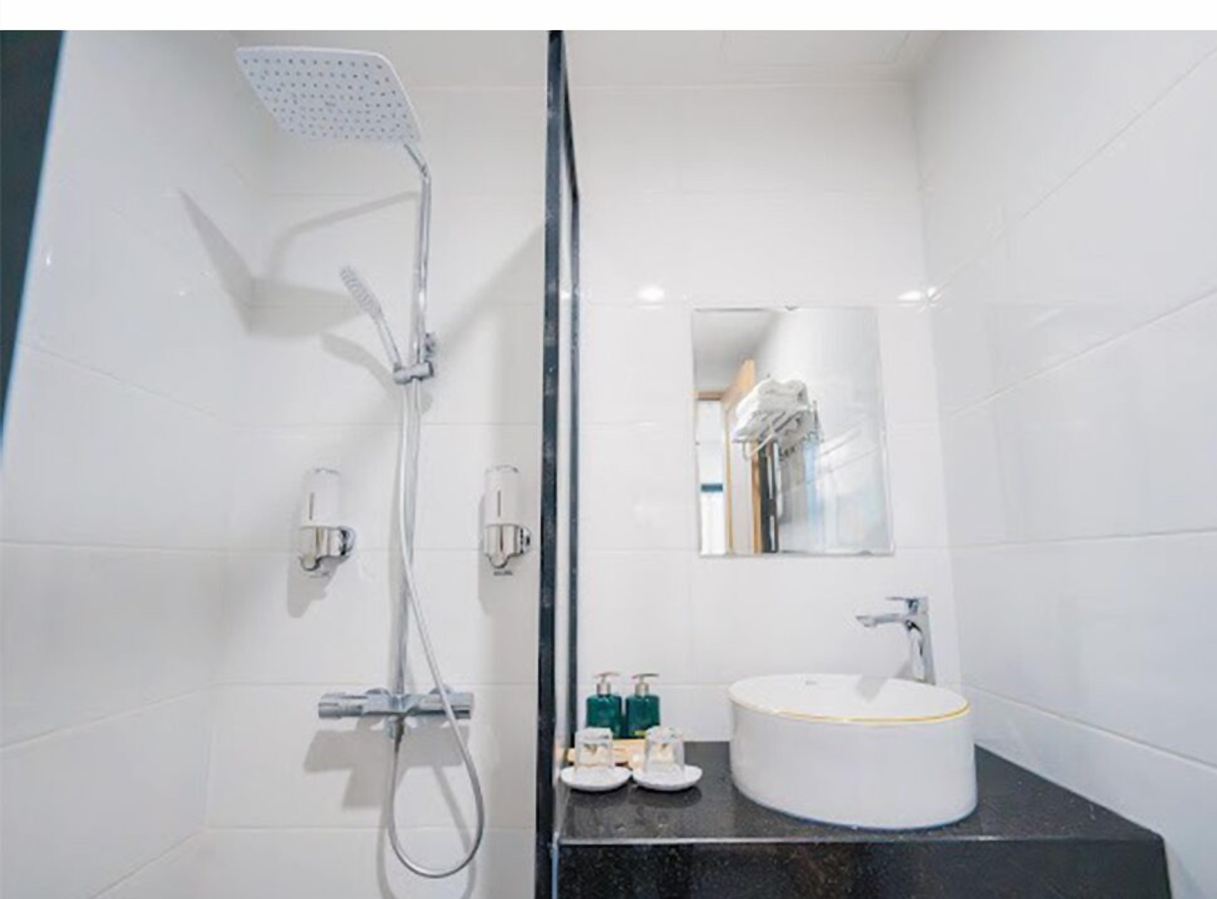 Een moderne badkamer met een douche, wastafel en spiegel.