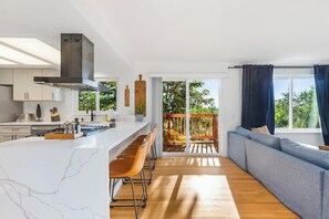 Eine moderne Küche mit Marmorarbeitsplatte, Holzbarhocker und einer großen Kochinsel.