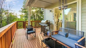 A wooden deck with a grill, outdoor seating, and a hanging light fixture. - Bodur's Rustling Leaves - EV Charge, BBQ, Privacy (Renton)