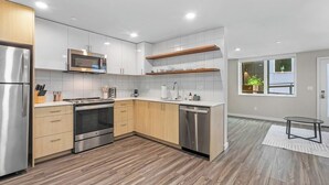 Une cuisine moderne dotée d’appareils électroménagers en acier inoxydable, de meubles en bois et d’un dosseret carrelé.