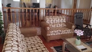 A living room with a sofa set, a small table with a vase and a book, and a chair. - Beautiful One Bedroom with WiFi in Brumalia Mandeville, Manchester (Mandeville)
