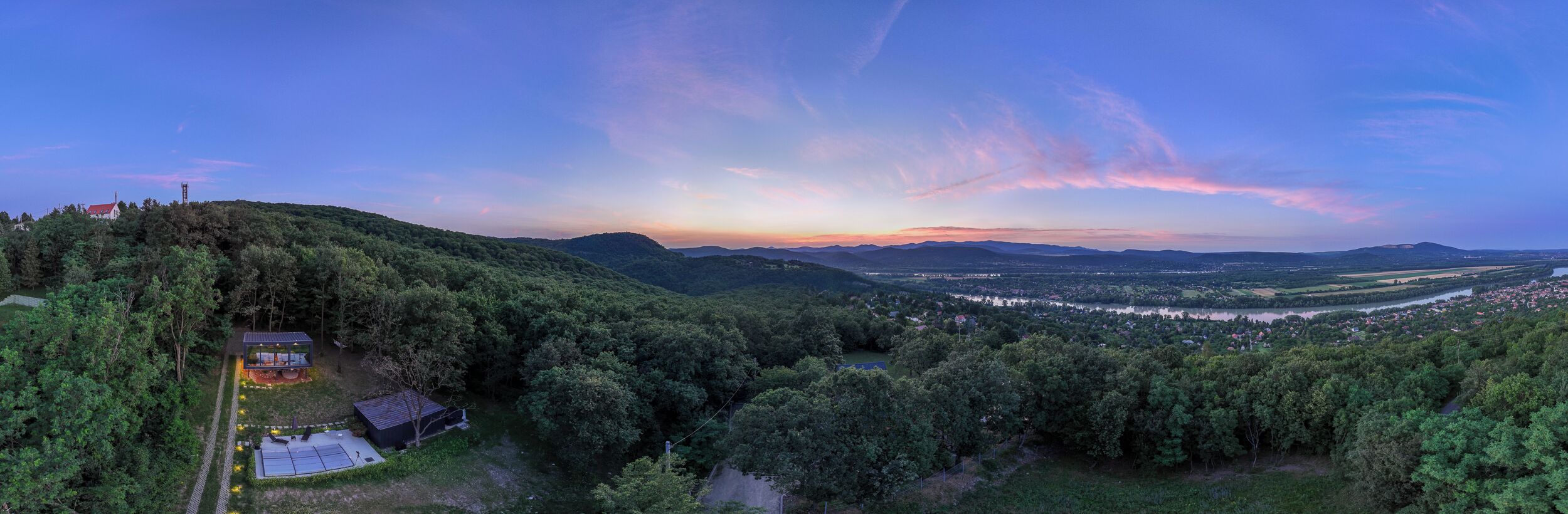 Uma vista panorâmica de uma paisagem montanhosa com um rio e um pequeno povoado.