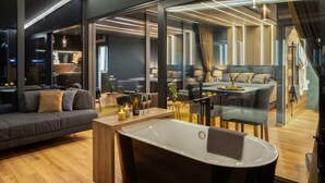 Una sala moderna con una bañera grande, un sofá y un comedor con mesa lista para dos.