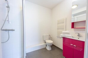 A bathroom with a shower, toilet, and pink vanity with a mirror. - Le Campus Appartement (Nice)