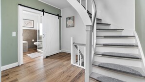 Una escalera con barandal blanco y piso de madera.