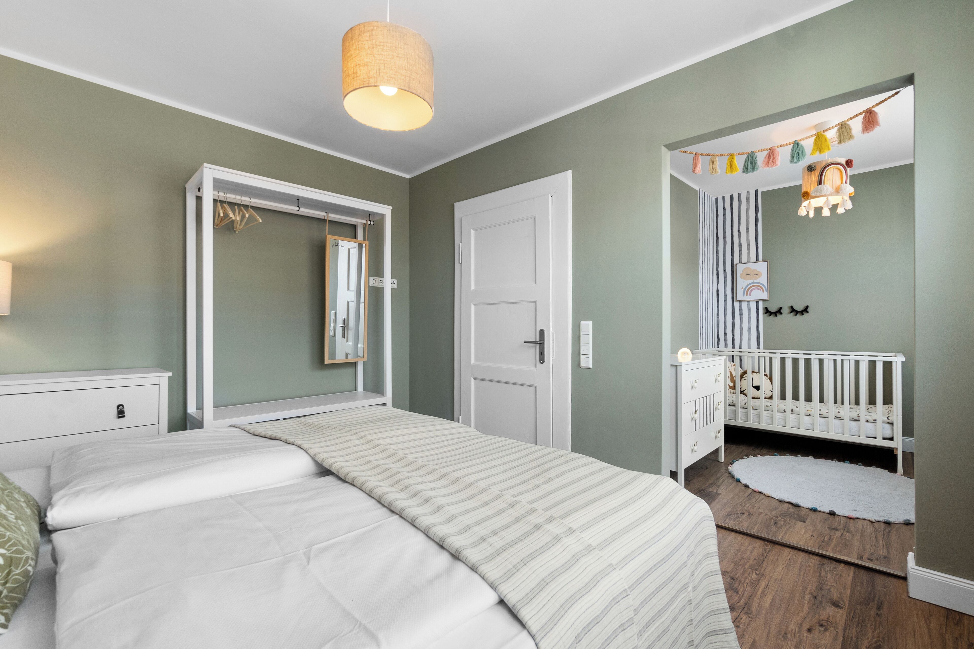 Un dormitorio con cama, cuna, armario y puerta.